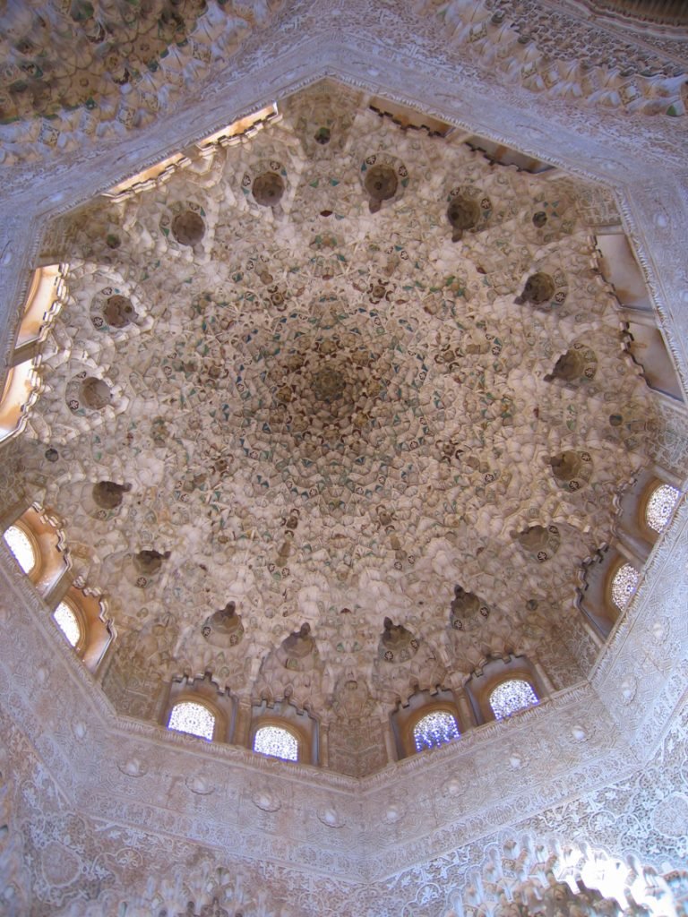 Sobre estas líneas, bóveda de mocárabes de la Sala de las dos Hermanas. Arriba, de izquierda a derecha, vistas de la Alhambra y el Patio de los Leones.